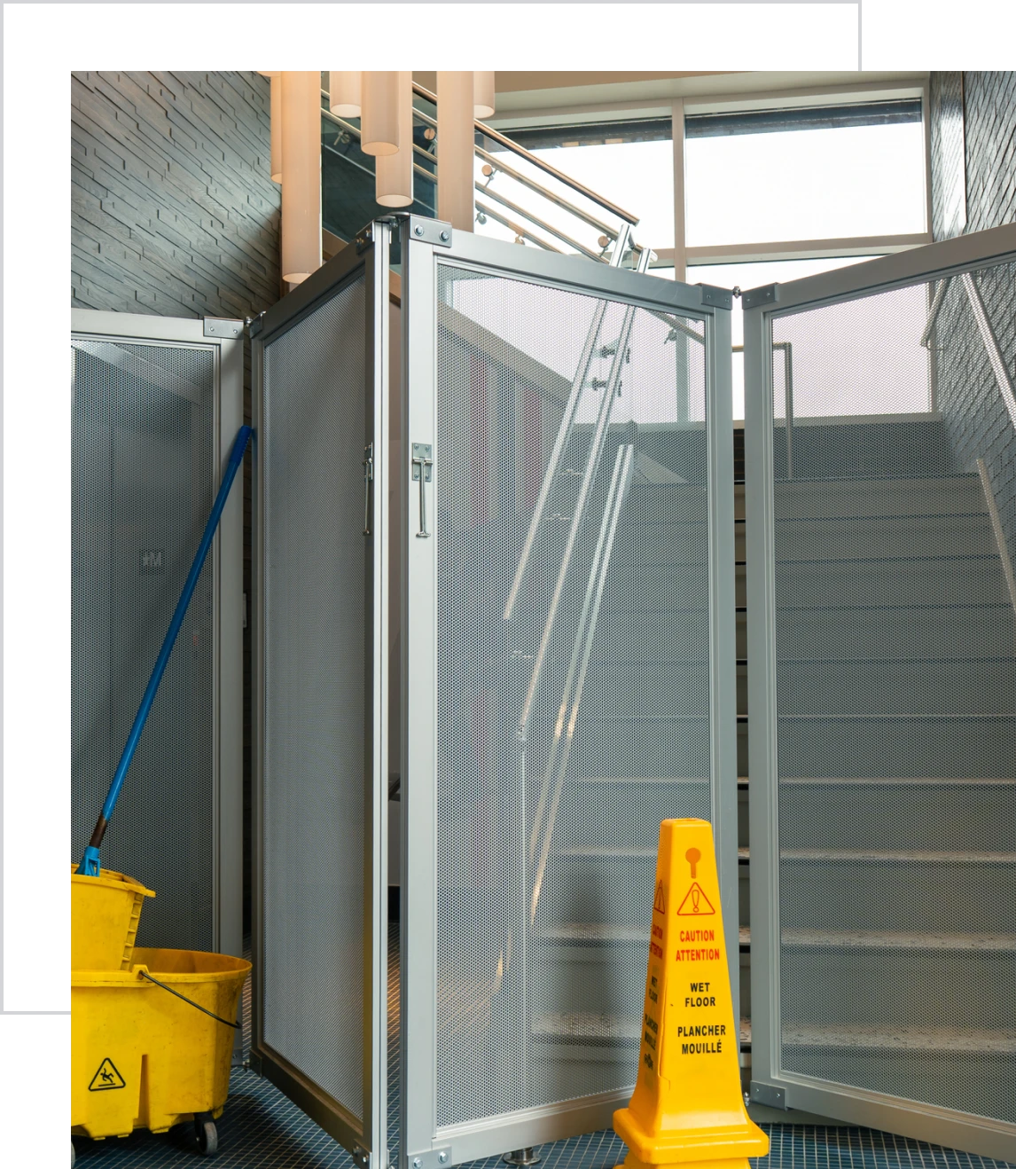 Wet floor sign beside mop and stairs.